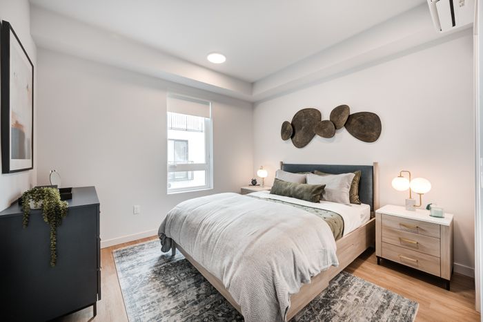 Elegant bedroom with modern decor, featuring a cozy bed with plush cushions, stylish lighting, and chic wall art.