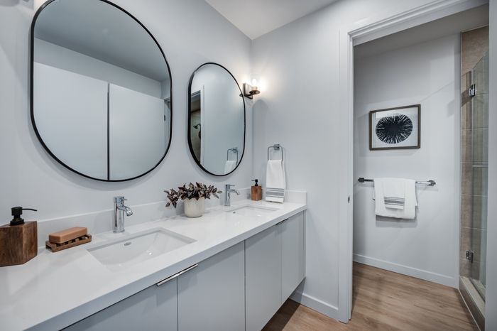 Modern bathroom with sleek double vanity, large circular mirrors, and stylish decor accents.