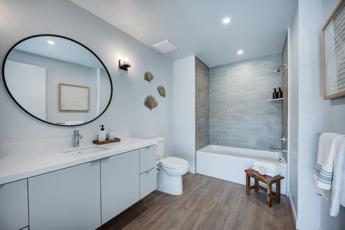 Modern bathroom with sleek vanity, large round mirror, stylish decor, and inviting bathtub, perfect for relaxation.