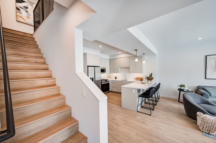 Modern open-concept living space with elegant kitchen, cozy sitting area, and inviting staircase.