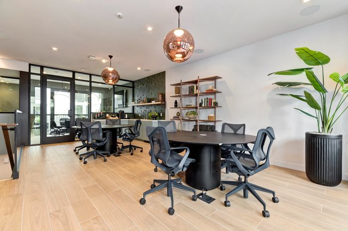 Contemporary meeting space with stylish furniture, modern lighting, and vibrant greenery, creating an inviting workspace.