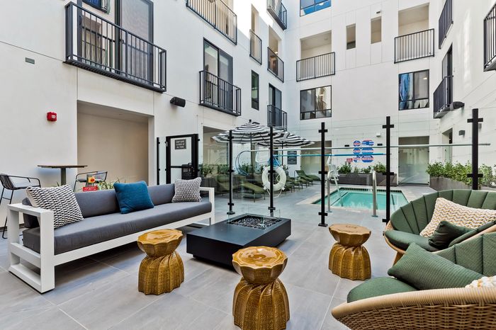 Chic courtyard with modern seating, unique golden tables, and a refreshing pool for ultimate relaxation and style.