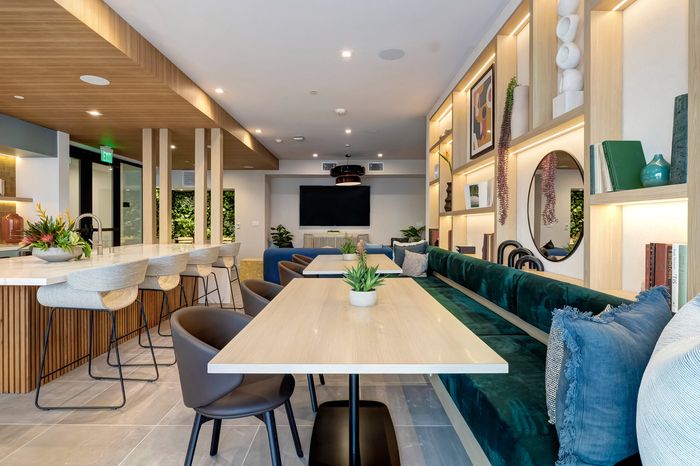 Modern communal space featuring sleek wooden interiors, plush seating, and vibrant greenery accents, ideal for relaxation and social gatherings.
