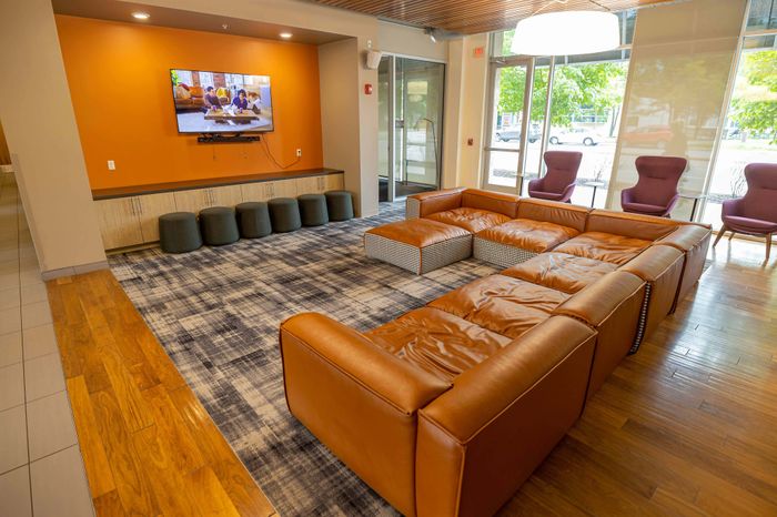 Inviting modern lounge area featuring a luxurious leather sectional sofa, plush carpeting, and large windows for natural light.