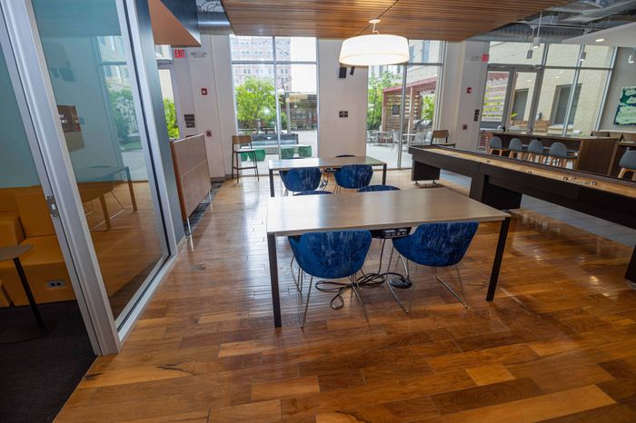 Modern communal lounge with sleek tables, vibrant blue chairs, and inviting natural light through large windows.
