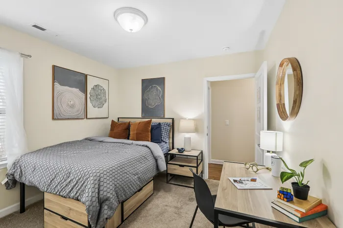 Inviting bedroom with cozy bed, modern decor, and a functional desk space bathed in natural light.