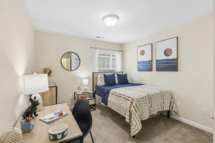 Cozy bedroom with elegant decor, featuring a stylish bed with geometric bedding, a modern desk, and chic wall art.