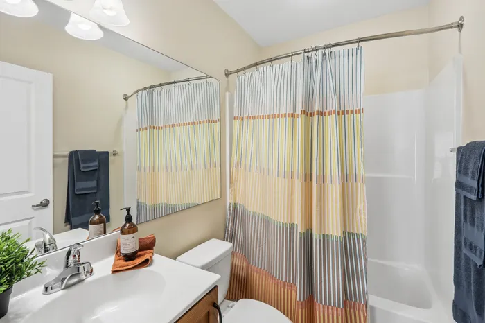 Bright and modern bathroom with striped shower curtain, sleek vanity, and decorative accents.