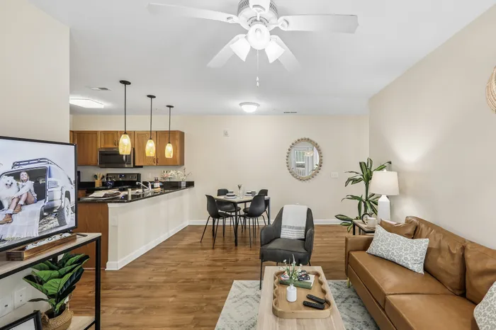 Inviting apartment interior featuring an open-plan kitchen with elegant pendant lights, cozy living space with a leather couch, and a modern dining area.