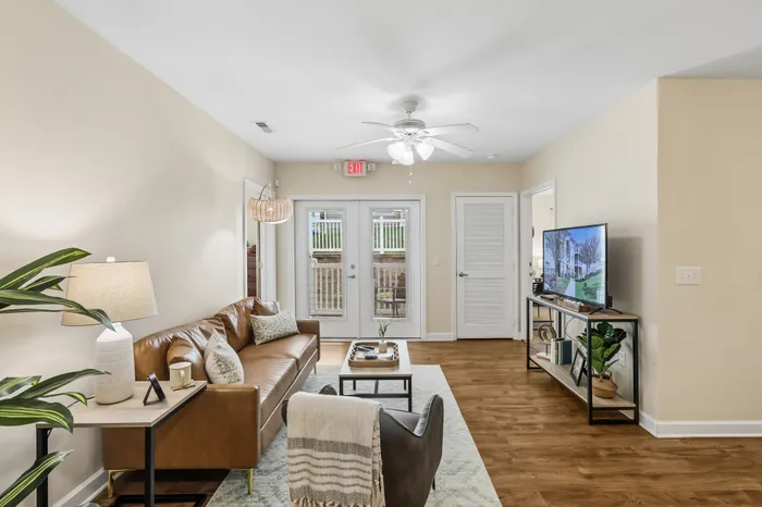 Inviting living room with a stylish leather sofa, modern decor, and welcoming natural light through glass doors.