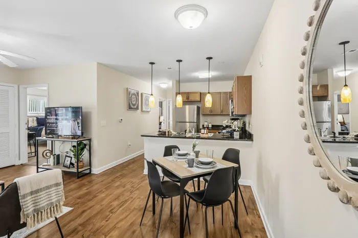 Modern open-concept living and dining area featuring a sleek kitchen with pendant lighting, cozy seating, and beautiful hardwood floors.