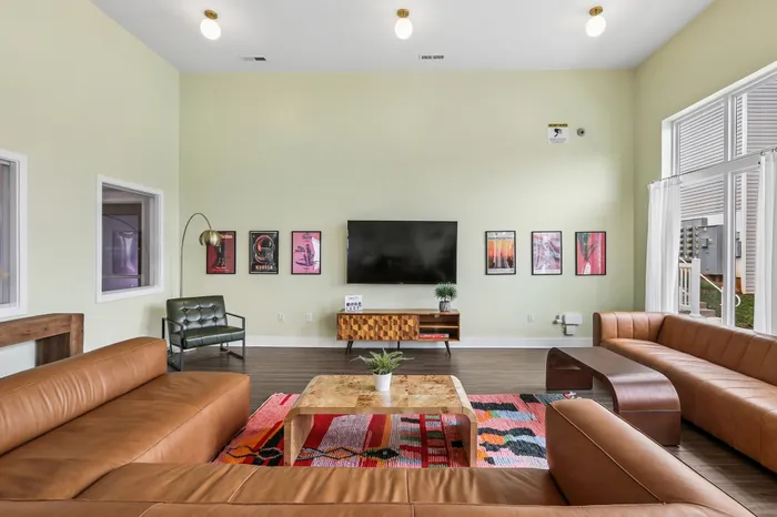 Contemporary living room with stylish leather sofas, vibrant wall art, and a large flat-screen TV, creating a sophisticated and inviting atmosphere.