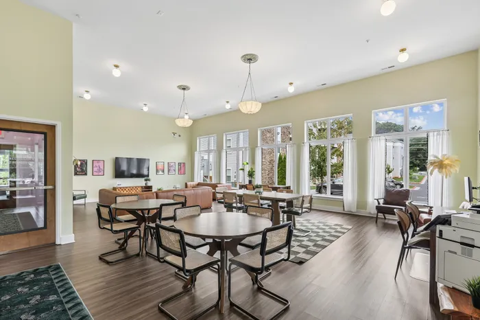 Bright and spacious community room with large windows, modern seating, and elegant lighting, offering a welcoming ambiance.