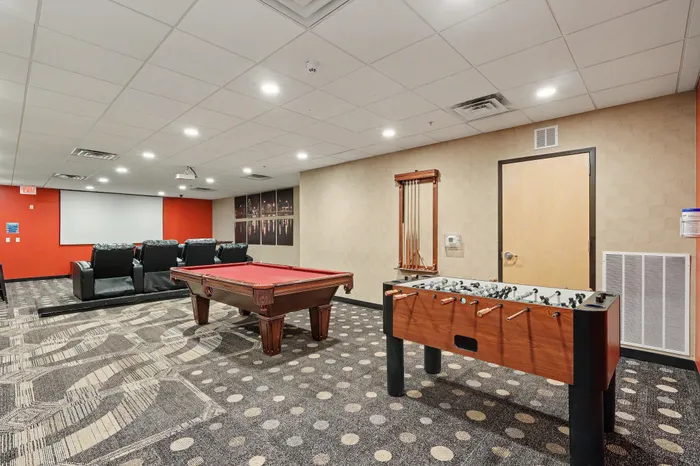 Inviting entertainment room with plush theater seating, pool table, and foosball table, perfect for social gatherings and fun.
