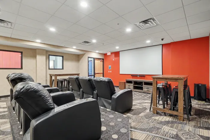 Luxurious home theater room with plush leather recliners, a large projection screen, and stylish modern decor.