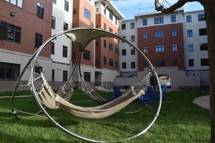Modern apartment complex courtyard featuring relaxing hammocks and inviting seating areas surrounded by lush greenery.