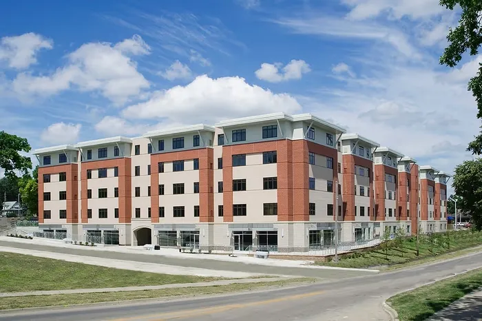 Modern apartment complex with contemporary design, featuring red brick exterior set against a clear blue sky.