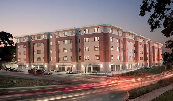 Modern apartment building with sleek architecture, illuminated windows, and vibrant night ambiance.
