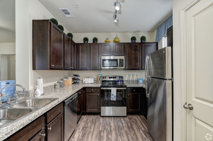 Modern kitchen with sleek dark wood cabinetry, stainless steel appliances, and polished granite countertops, perfect for culinary enthusiasts.