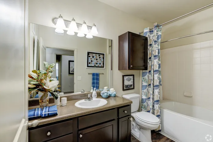 Elegant bathroom showcasing a modern vanity, stylish decor, and inviting tub with a floral shower curtain.