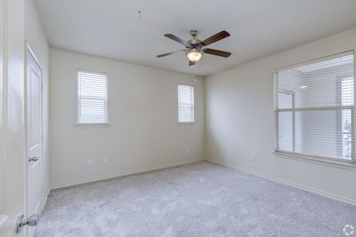 Bright spacious room with soft carpet, large windows, and an elegant ceiling fan, offering a perfect blend of comfort and style.