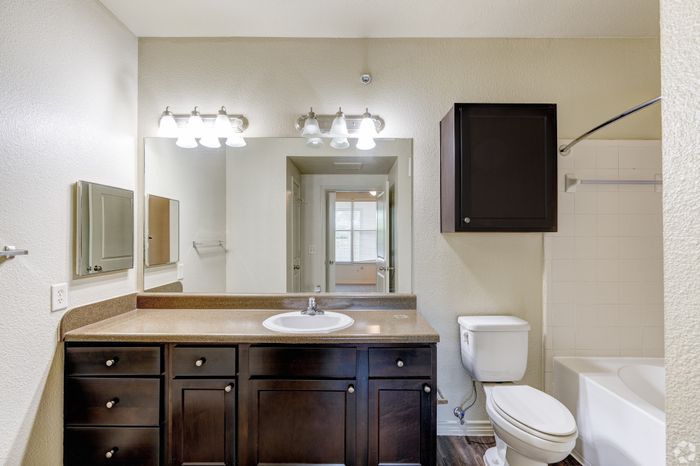 Elegant bathroom with modern lighting, sleek countertop, and dark wood cabinetry, offering a touch of luxury and comfort.