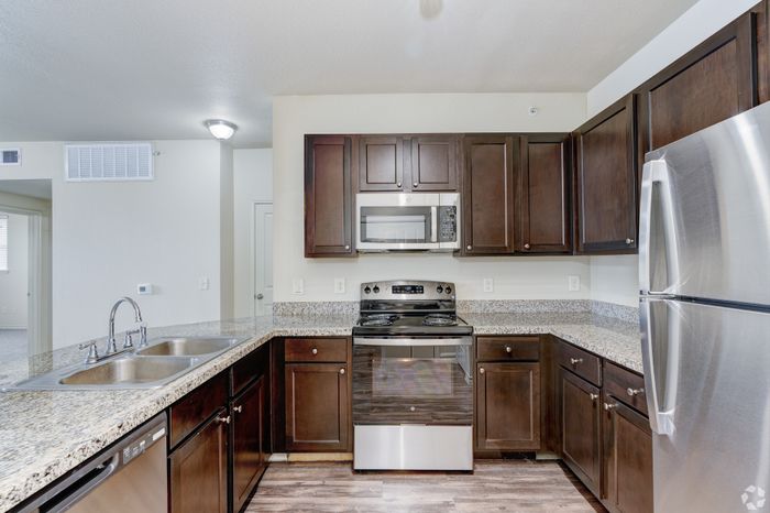 Modern kitchen with sleek stainless steel appliances, dark wood cabinetry, and granite countertops creating a sophisticated and functional cooking space.