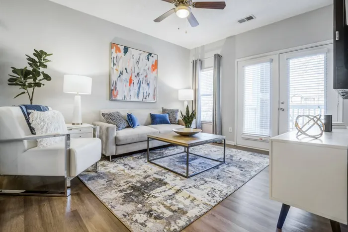 Model living room at our apartments for rent in Mooresville, featuring wood grain floor paneling and doors to the balcony.