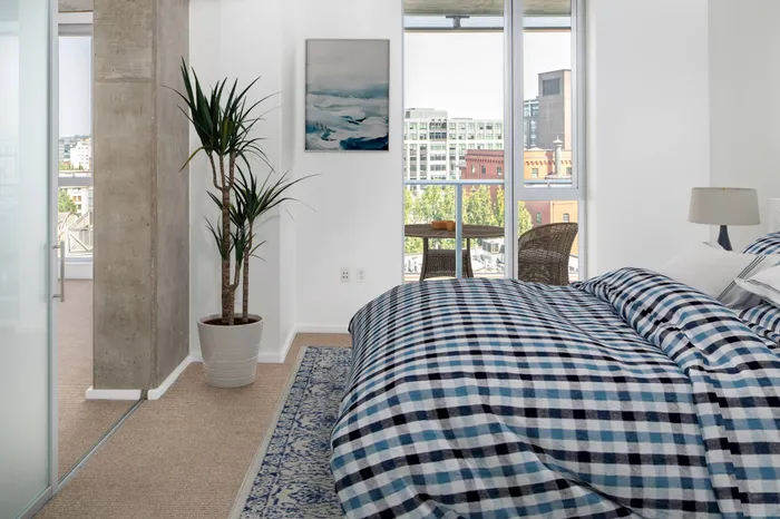 Model bedroom at our apartments in Portland, OR, featuring white and blue bedspread and floor to ceiling windows.