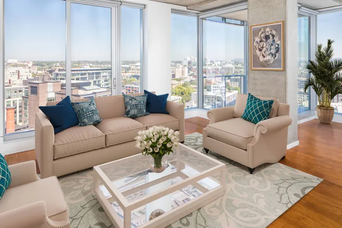Penthouse Model living room at our apartments in Portland, OR, featuring cushioned couches and floor to ceiling windows.