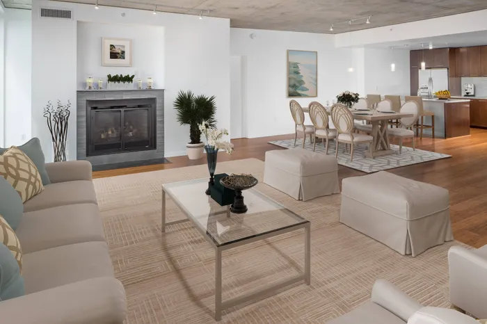 Penthouse home including cushioned couch, fireplace, dining room and kitchen.