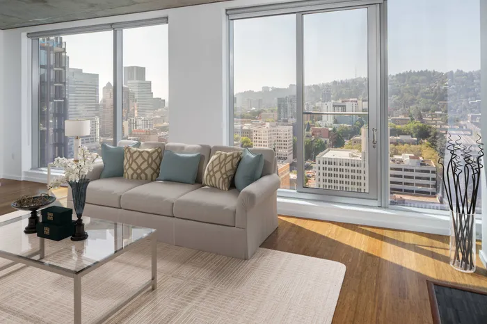 Model living room at our apartments in Portland, OR, featuring cushioned couches and floor to ceiling windows.