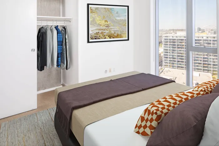 Model bedroom at our apartments in Portland, OR, featuring white and blue bedspread and floor to ceiling windows.