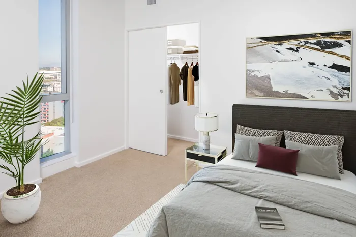 Model bedroom at our apartments in Portland, OR, featuring white and blue bedspread and floor to ceiling windows.