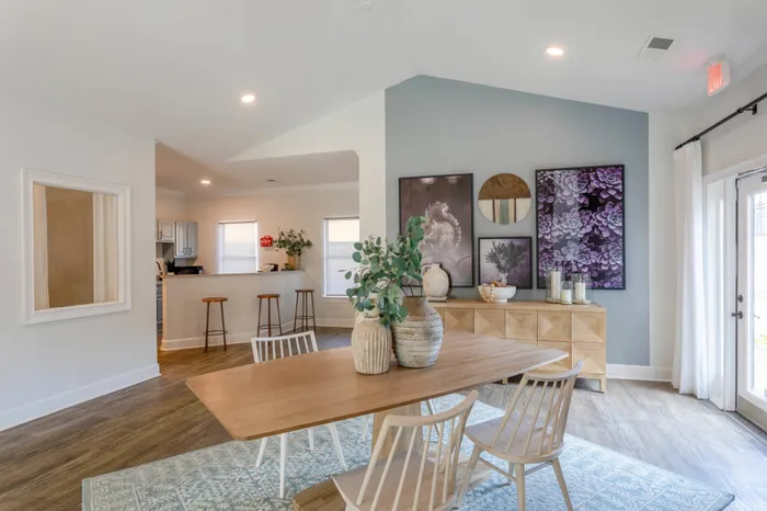 Community clubhouse featuring dining table, credenza, and view into community kitchen's bar seating with three bar stools