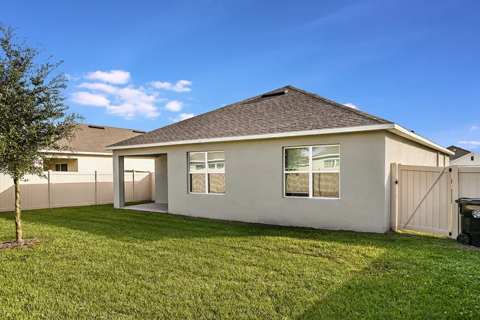 Exterior view of a home for rent with a patio. Beautifully landscaped, fenced in backyard, at a home for rent in Apopka, Florida.