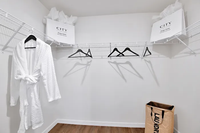 Walk in closet at our homes in Apopka, FL, featuring white clothing racks, clothes hangers, and robes.