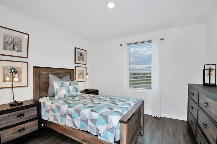 Model bedroom in one of our homes in Apopka, FL, featuring wood grain floor paneling and wooden furniture.