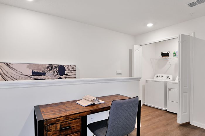 Detail of the interior of our townhomes in Apopka, FL, featuring a desk with a book and in unit laundry closet.