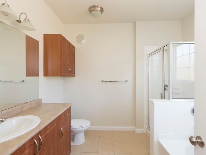 Model bathroom at our apartments in Marlborough, featuring tan tile floor paneling and a shower and bath.