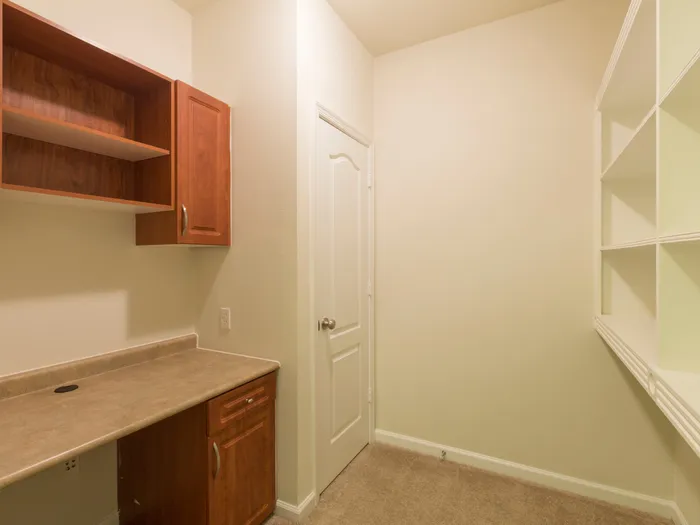 Empty office at our apartments in Marlborough, featuring carpeted flooring, a desk with built in shelves.