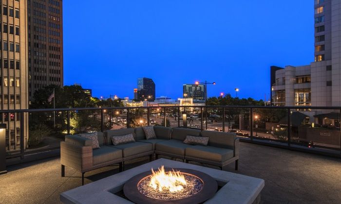 Rooftop lounge at our apartments for rent in Atlanta, featuring a fire pit, outdoor couches, and a view of the city.