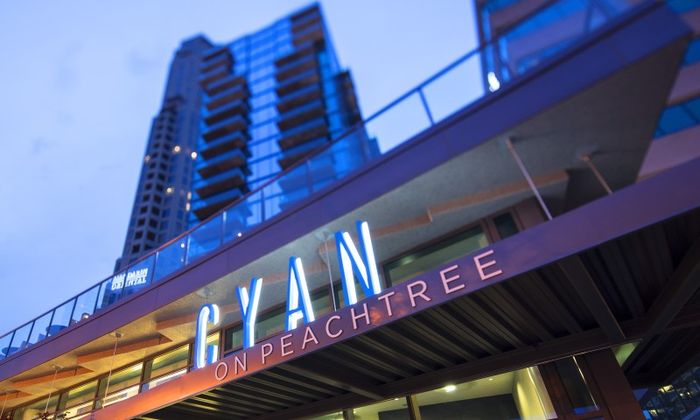 The entrance to the Cyan on Peachtree apartment complex in Atlanta, GA, featuring a lit up sign above the entrance.