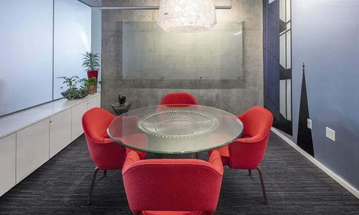 Conference room and co working space at our apartments in Portland, OR, featuring red chairs and a glass board for writing on.