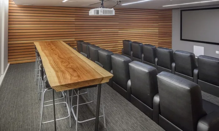 Theater and entertainment room at our apartments in Portland, OR, featuring rows of chairs, a projector, and a conference table.