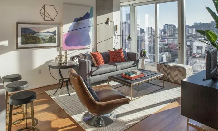 Model living room at our apartments in Portland, OR, featuring a leather chair, colorful decor, and a flat screen TV.
