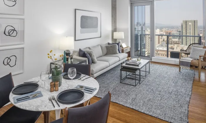 Model living room at our apartments in Portland, OR, featuring cushioned couches and floor to ceiling windows.