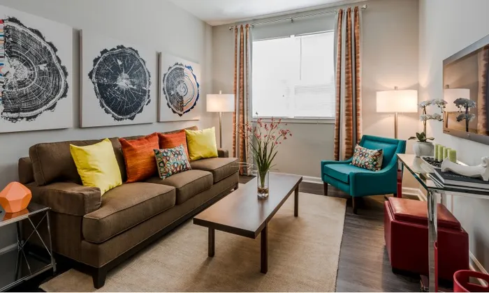 Model living room at our apartments for rent in Washington, DC, featuring a flat screen TV, couch, and windows with curtains.