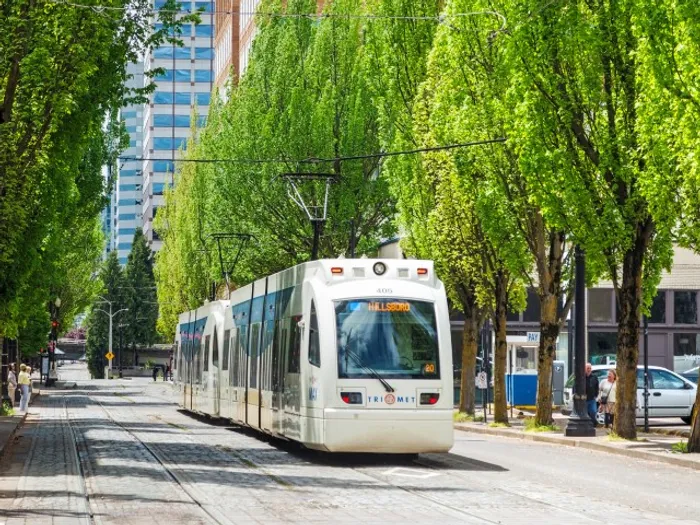 Photograph of a public transit vehicle in Portland, OR. There are green trees and a quiet city street.