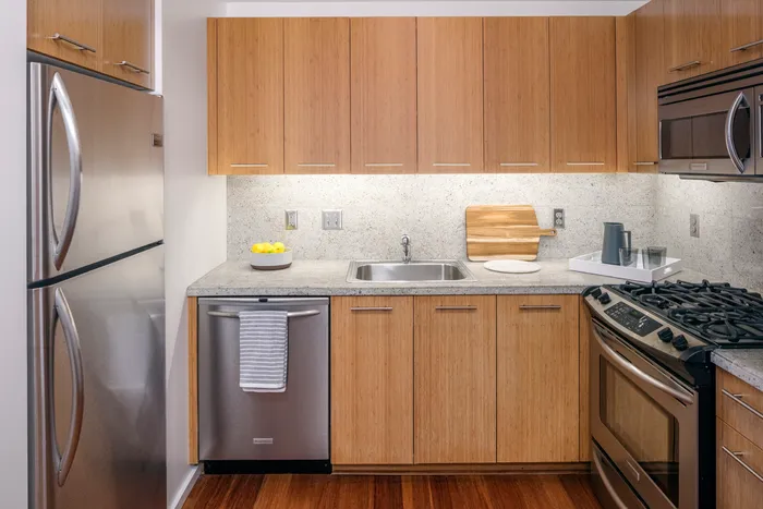 Close up view of a kitchen with light wooden cabinetry and granite countertops inside an apartment in downtown Portland.